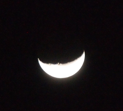 [Against a black sky is a bright white crescent with irregular edges in the center due to the craters on the moon. The crescent is at the bottom on the sphere from about 3 o'clock to 8 o'clock.]